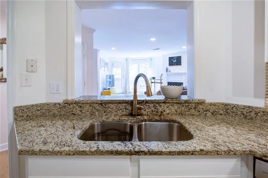 Kitchen featuring light stone counters, recessed lighting, and white cabinets