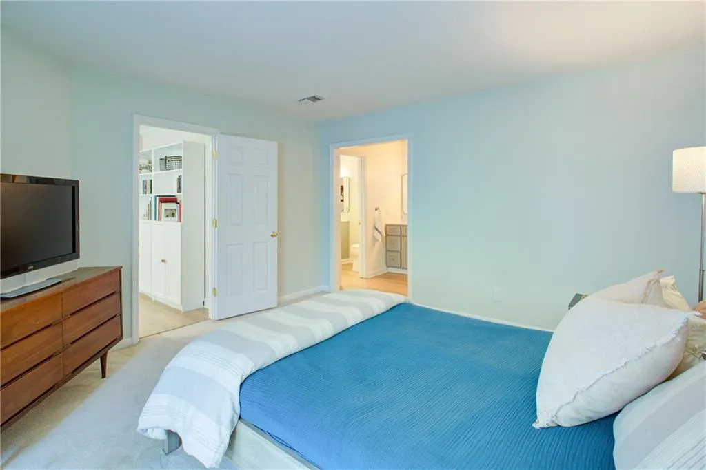 Bedroom featuring light colored carpet and connected bathroom