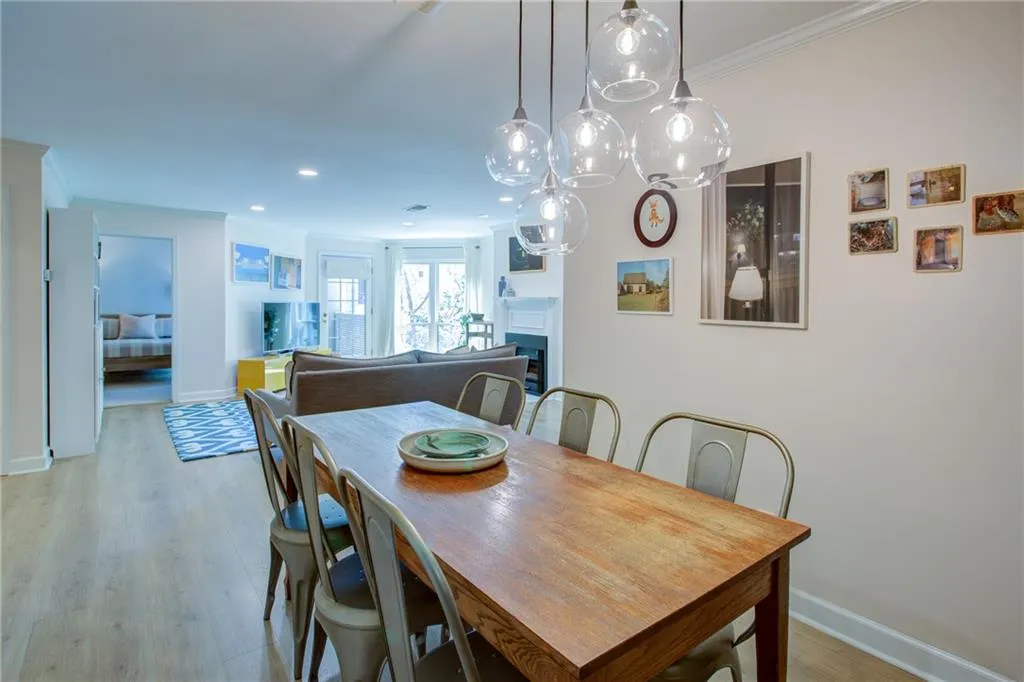 Dining area with ornamental molding, light wood finished floors, recessed lighting, and a fireplace