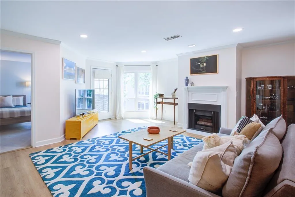 Living room featuring wood finished floors, ornamental molding, recessed lighting, and a fireplace