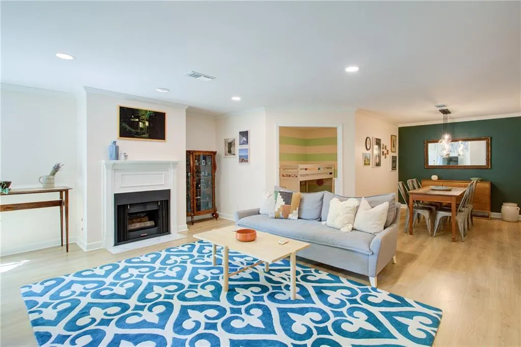 Living area with light wood-style flooring, crown molding, a chandelier, a fireplace with flush hearth, and recessed lighting