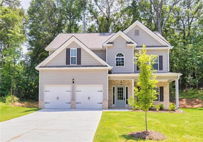 Two-story exterior with light gray siding, a covered porch, a two-car garage, and a concrete driveway