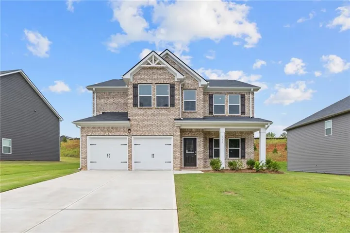 Two-story brick facade, two-car garage, covered entry with columns, gabled architectural details, and mature landscaping