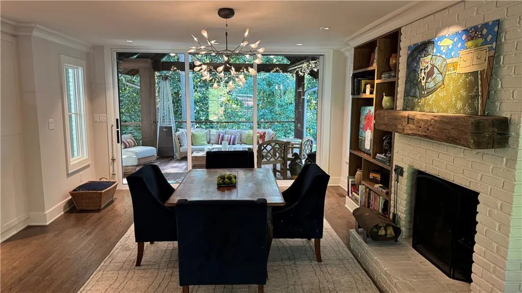 Eat in Kitchen area featuring wood finished floors, a chandelier, crown molding, a brick fireplace, and a wall of windows