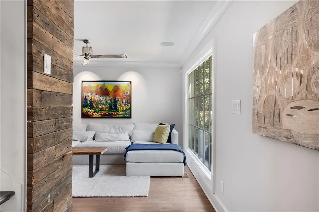 View into den area featuring crown molding, wood finished floors, and a ceiling fan