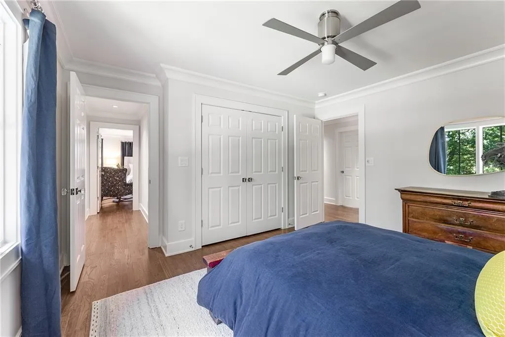 Bedroom with ornamental molding, wood finished floors, a closet, and a ceiling fan
