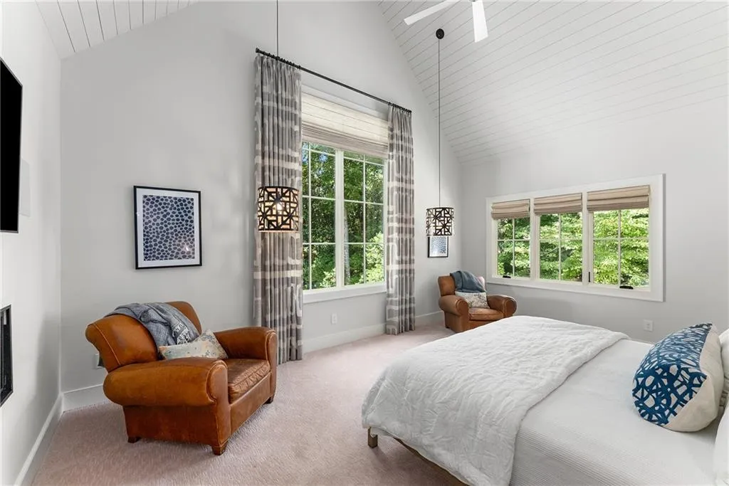 Primary Bedroom with carpet flooring, high vaulted ceiling, multiple windows, and a skylight