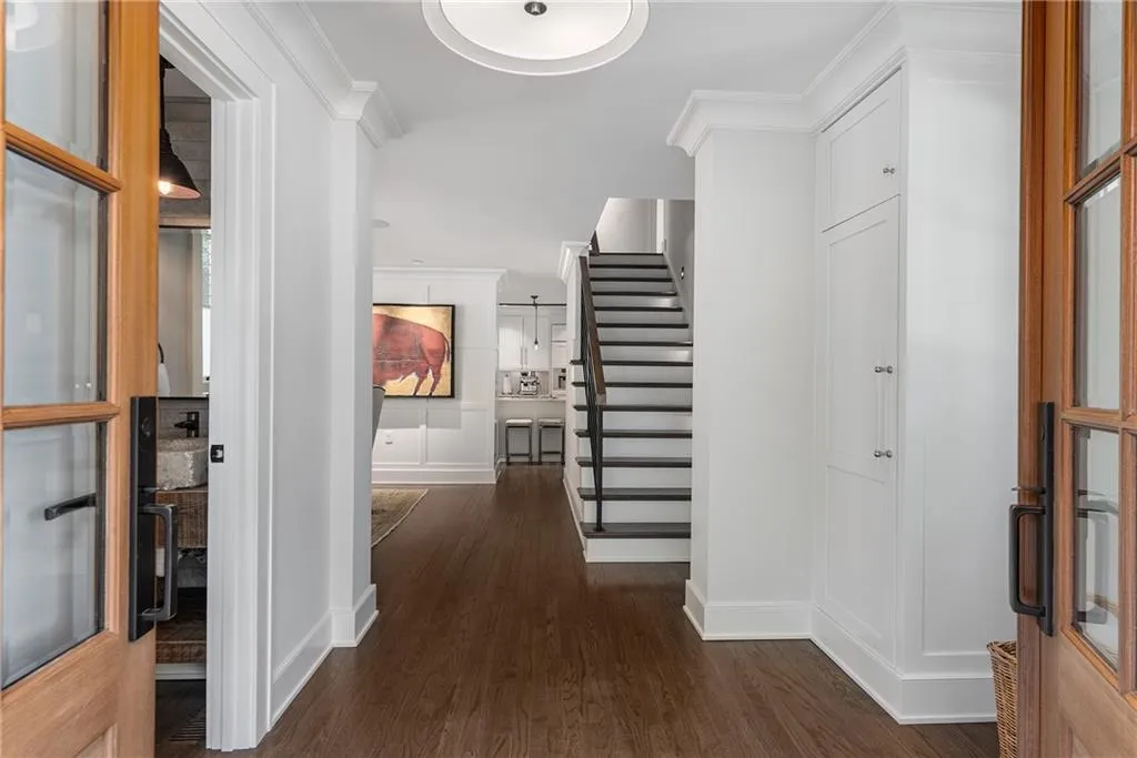 Double door entry hallway featuring stairway, dark wood-style floors, and crown molding