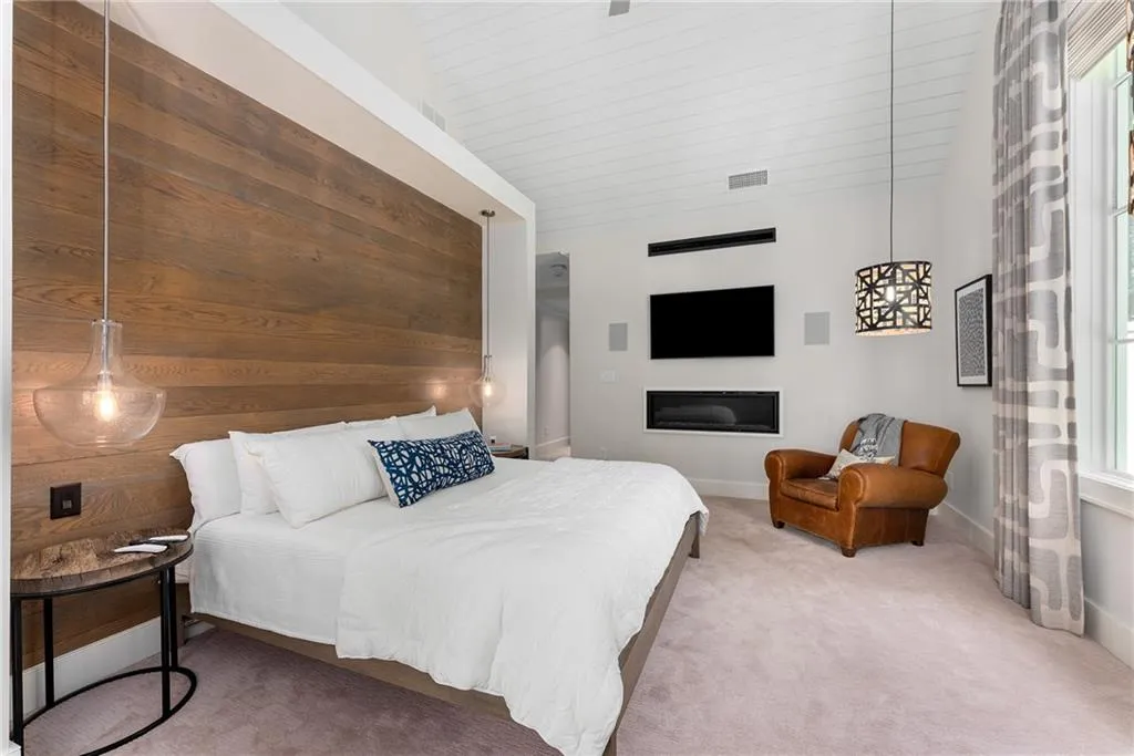 Primary bedroom with multiple windows, high vaulted ceiling, and wood accent wall