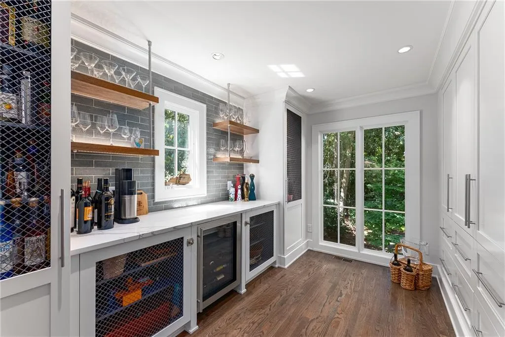 Butler's pantry with dry bar, crown molding, decorative backsplash, dark wood-style floors, open shelves, and wine fridge