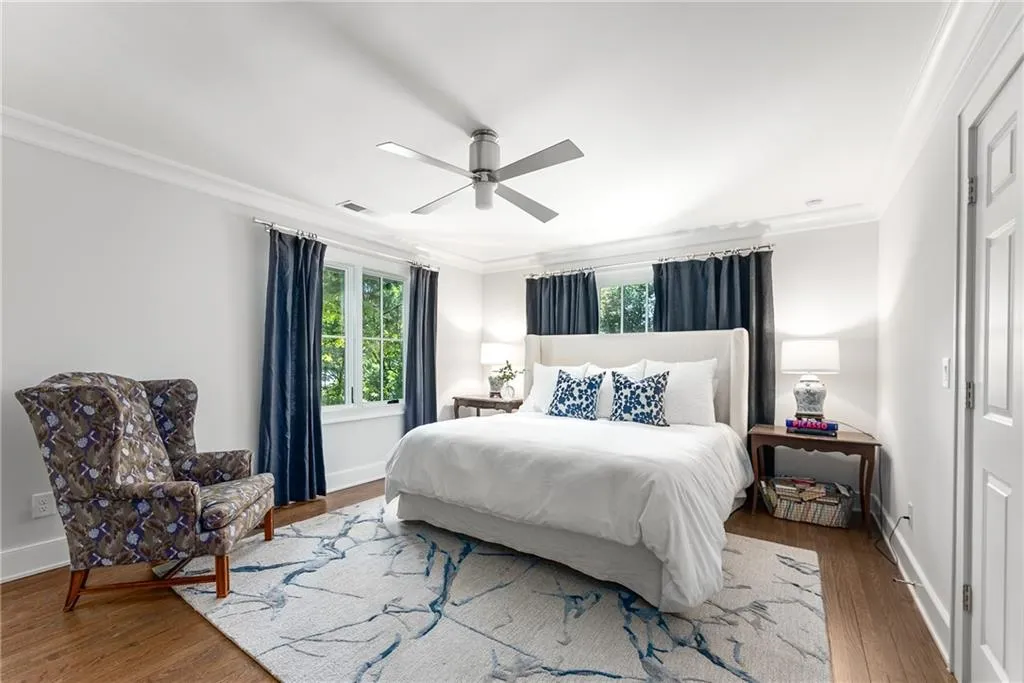 Bedroom with ornamental molding, multiple windows, wood finished floors, and ceiling fan