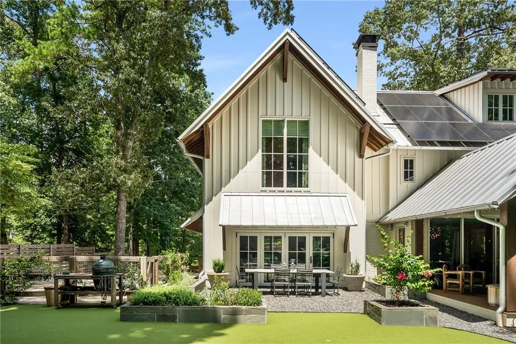 Back of property with board and batten siding, a chimney, a metal roof, a standing seam roof, and a patio