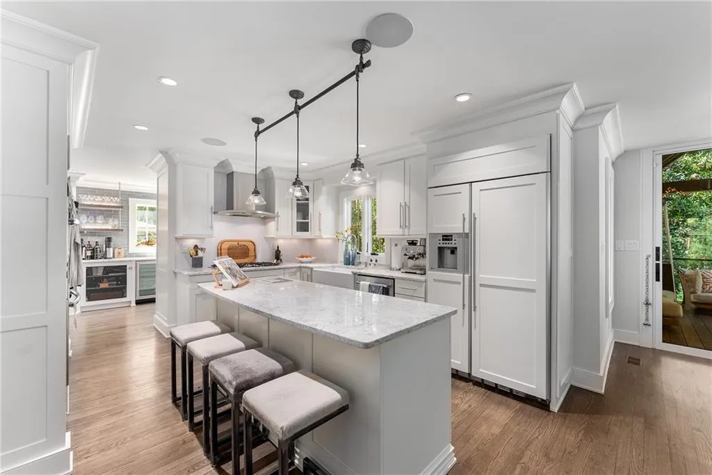 Kitchen featuring Carrera countertops, paneled fridge, glass insert cabinets, dark wood-type flooring, and a kitchen breakfast bar