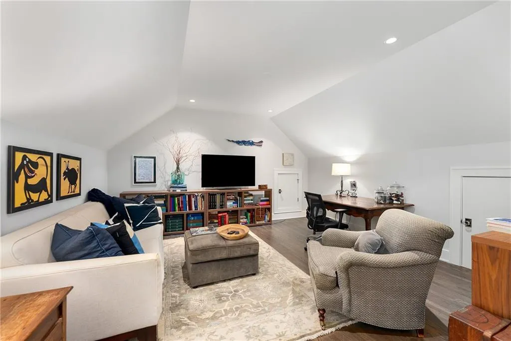 Living area featuring lofted ceiling, wood finished floors, recessed lighting, and a desk