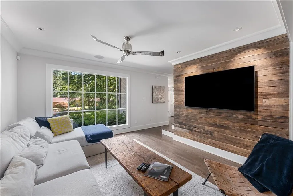 Den area with reclaimed wood siding ornamental molding, ceiling fan, and wood finished floors