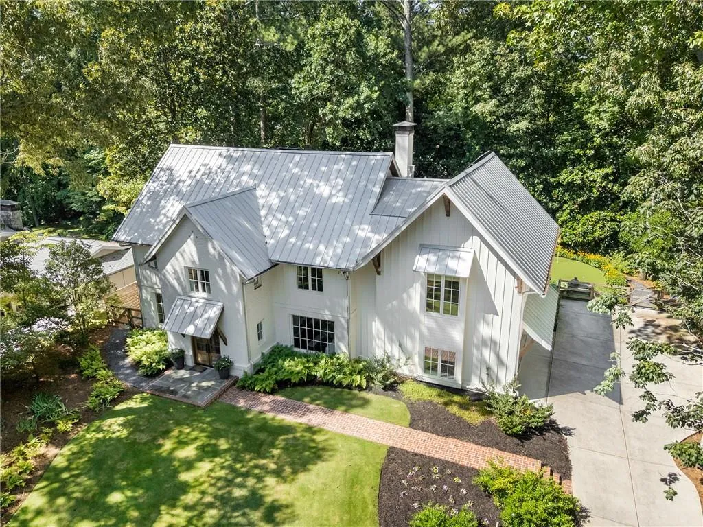 View of front facade with a front lawn, a metal roof, concrete driveway, a chimney, and a garage