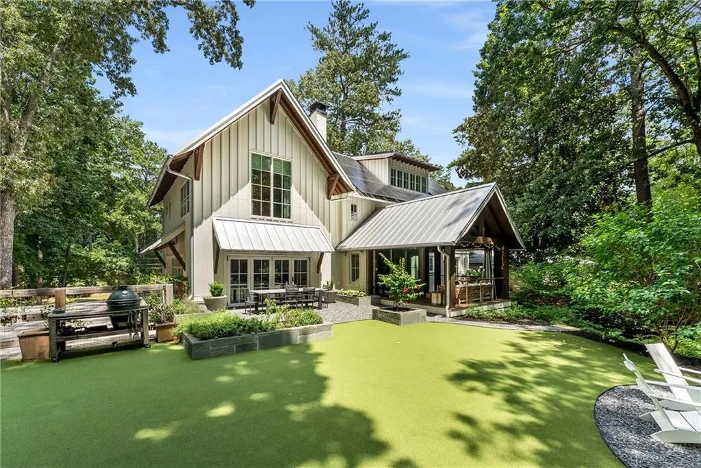 Rear view of property with board and batten siding, a patio, a chimney, a metal roof, and view of wooded area