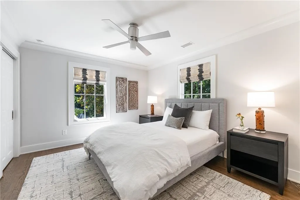 Bedroom with crown molding, wood finished floors, multiple windows, a ceiling fan, and a closet