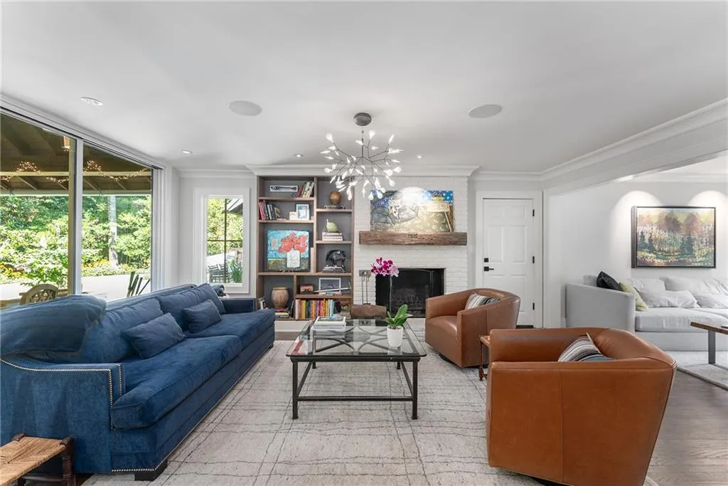 Living room with a brick fireplace, a chandelier, ornamental molding, wood finished floors, and recessed lighting