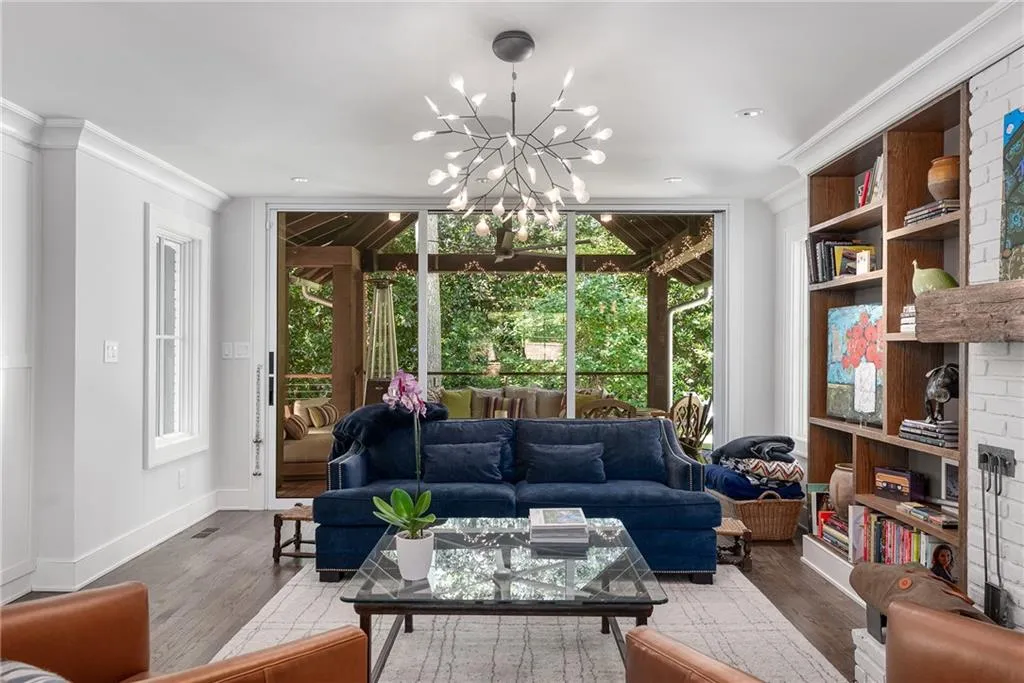 Living room with floor to ceiling windows, crown molding, wood finished floors, and a chandelier