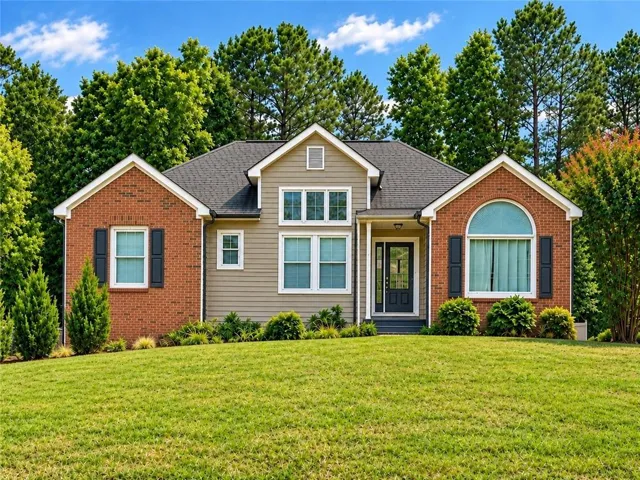 Brick and siding exterior with a gabled roofline, front entry porch, multiple window styles, and mature landscaping