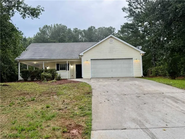 Single-story residence featuring light-colored siding, an attached garage, and a covered front porch