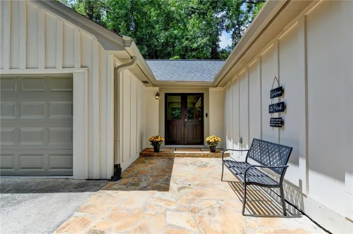 Flagstone pathway leading to a double dark wood entry door with glass panels, flanked by board-and-batten siding
