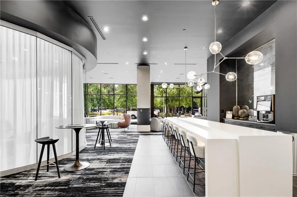 Bar with a wall of windows, recessed lighting, hanging light fixtures, dark tile patterned floors, and light stone counters