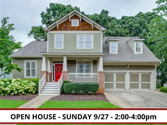 Two-story residence featuring a covered front porch, a vibrant red front door, and a two-car garage with individual doors