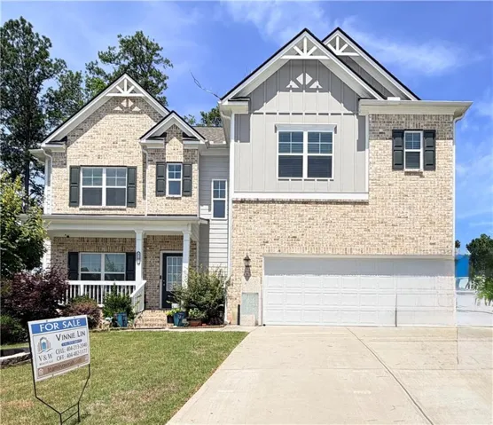 Two-story residence featuring a brick and siding exterior, a covered front porch with white pillars, and a two-car garage with a concrete driveway