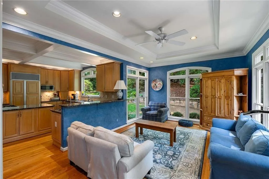 Living room with recessed lighting, hardwood flooring, a ceiling fan, crown molding, and a tray ceiling