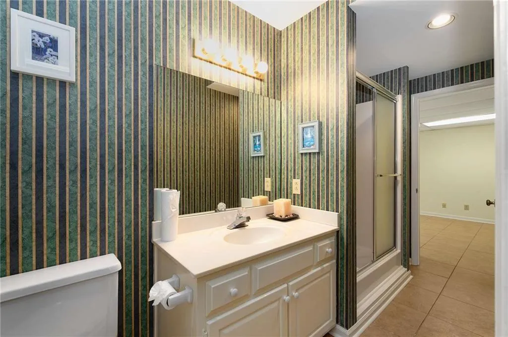 Full bathroom on terrace level with wallpapered walls, vanity, tile patterned floors, a shower with door, and recessed lighting