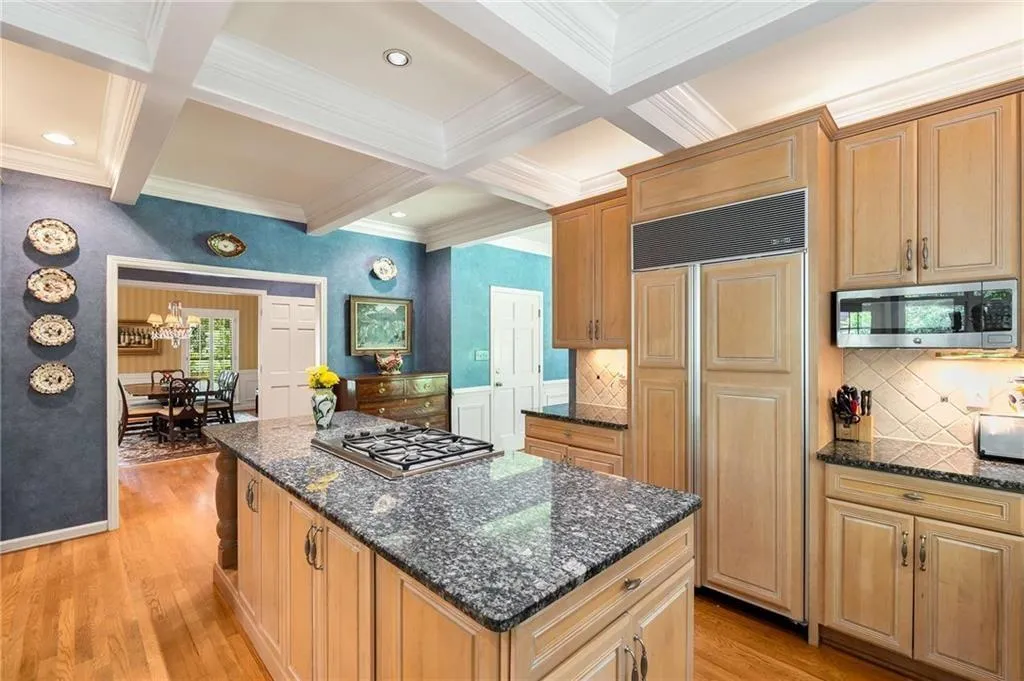 Kitchen featuring appliances with stainless steel finishes, coffered ceiling, beamed ceiling, tasteful backsplash, and hardwood floors.
