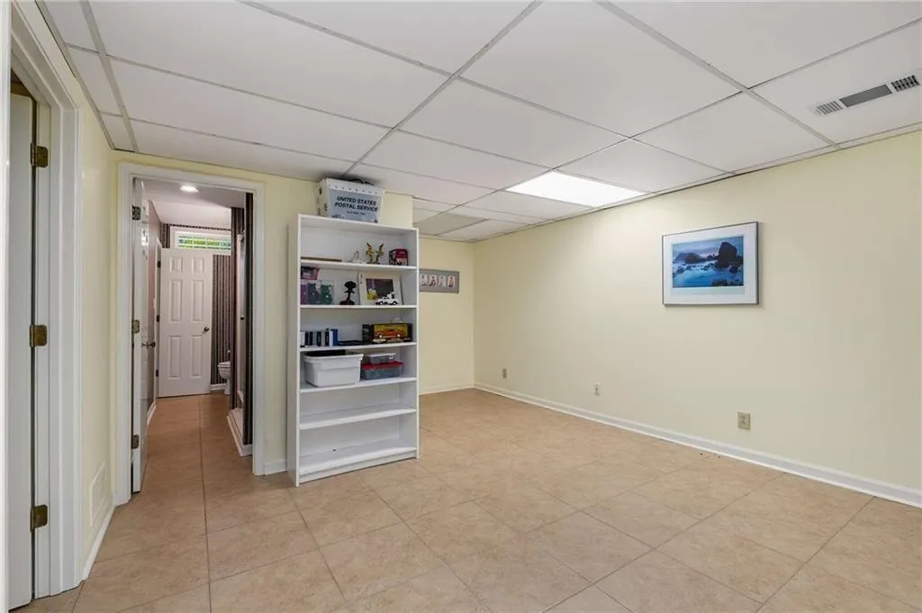 Finished basement with a drop ceiling and light tile patterned flooring