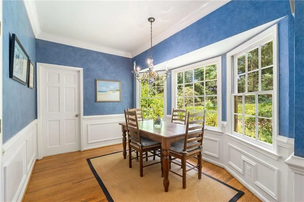 Kitchen Dining area featuring a decorative wall, a wainscoted wall, crown molding, a chandelier, and light wood-style flooring