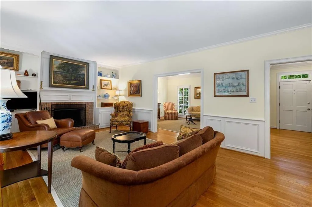 Den/Family Room featuring a wainscoted wall, a decorative wall, ornamental molding, hardwood finished floors, and a wood burning fireplace