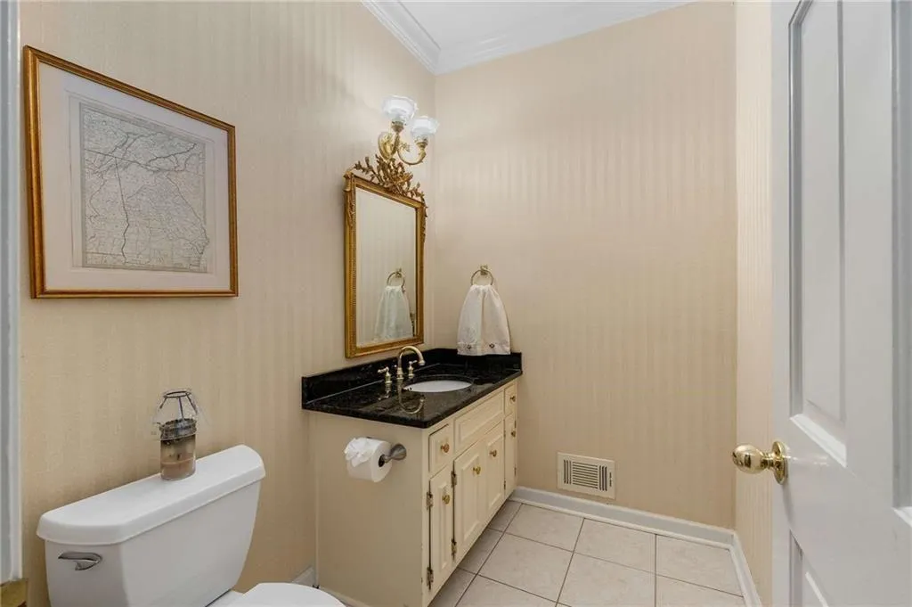 Main floor Half bath featuring wallpapered walls, crown molding, vanity, and tile patterned flooring
