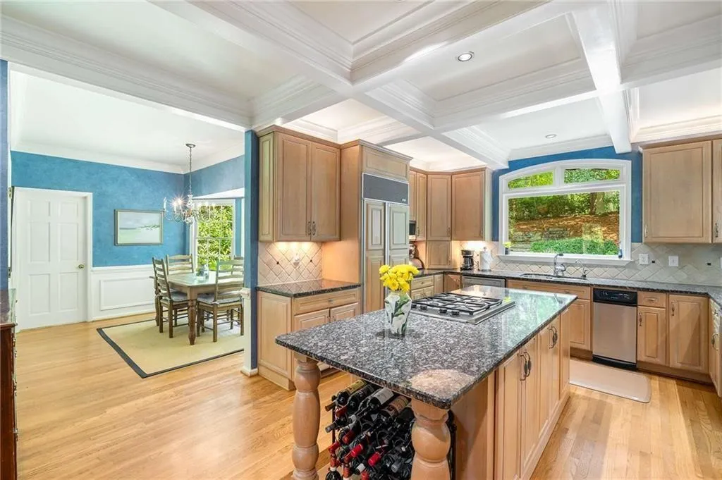 Eat in Kitchen with ornamental molding, coffered ceiling, beamed ceiling, light wood finished floors, and dark stone counters