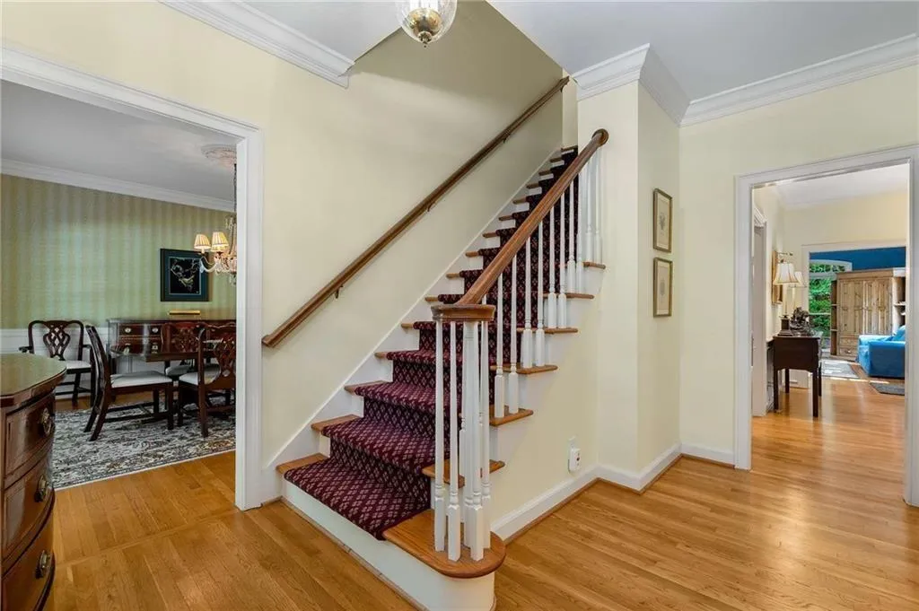 Stairway featuring crown molding, view towards dining room with chandelier, and wood finished floors