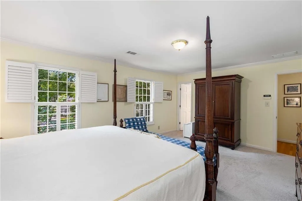 Bedroom with ornamental molding and light colored carpet