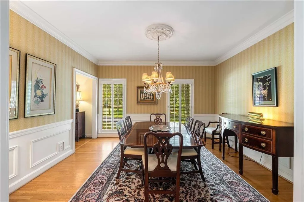 Dining room with wallpapered walls, ornamental molding, hardwood finished floors, a chandelier