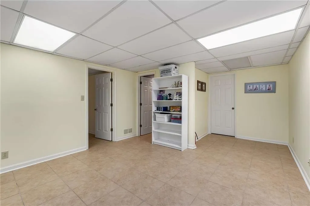 Large bonus room in basement with a paneled ceiling and baseboards