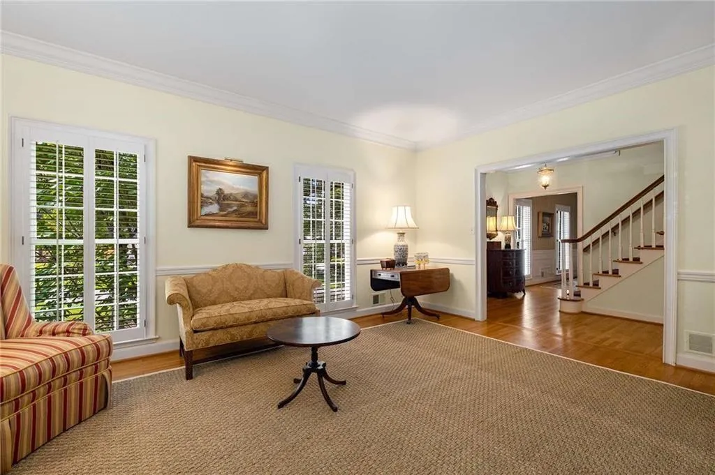 Light filled living room featuring hardwood flooring, high ceilings and a wainscoted wall