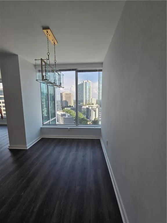 Unfurnished dining area featuring dark wood finished floors, a view of city, and a chandelier