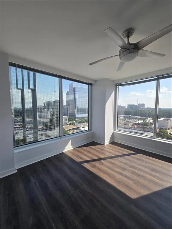 Empty room featuring a city view, wood finished floors, and ceiling fan