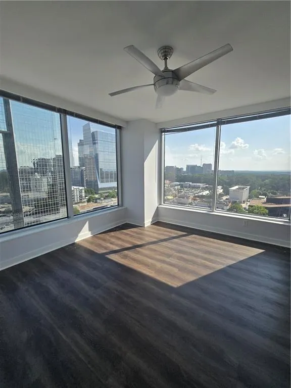 Unfurnished room featuring a view of city, ceiling fan, and wood finished floors