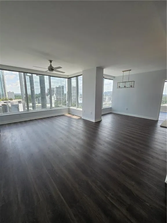 Unfurnished living room with ceiling fan and dark wood-style floors