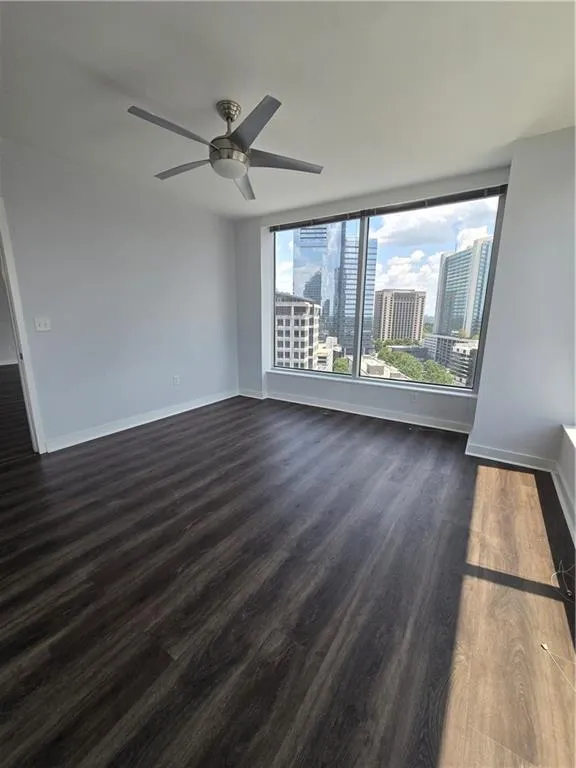 Spare room with a ceiling fan, dark wood-type flooring, and a city view