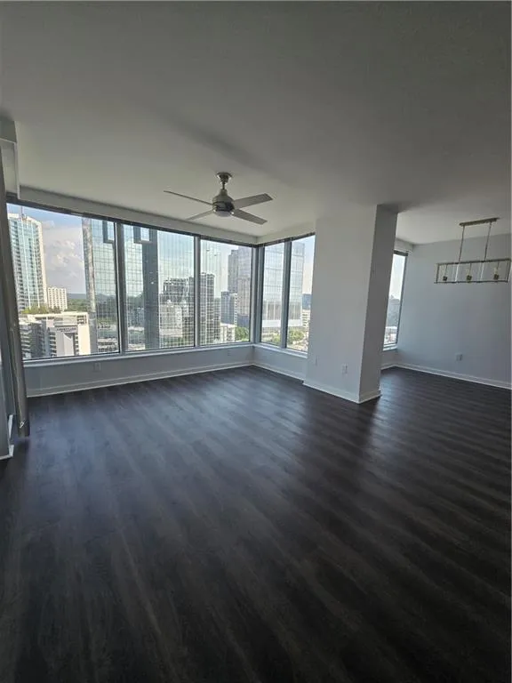 Unfurnished living room with dark wood-style flooring and a ceiling fan