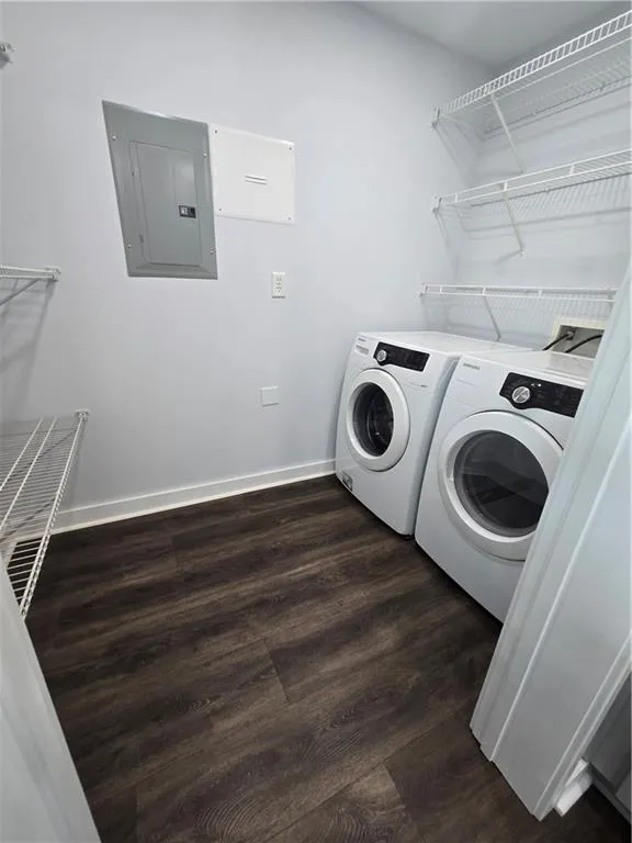 Laundry area with electric panel, washer and dryer, and dark wood-style floors